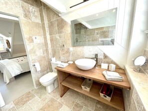Une salle de bain moderne avec un grand lavabo blanc, un meuble-lavabo en bois, une cabine de douche en verre et un grand miroir au-dessus du lavabo.
