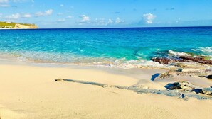 A beach with clear turquoise water, sandy shore, and rocky outcrops. - Beach front fabulous new all renovated unit 3 bedrooms 3 Baths, pools see view (Collectivité de Saint-Martin)