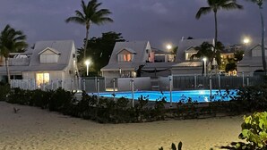 A beachfront hotel with multiple buildings, a swimming pool, and palm trees. - Beach front fabulous new all renovated unit 3 bedrooms 3 Baths, pools see view (Collectivité de Saint-Martin)