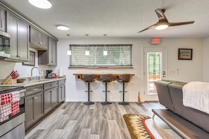 A modern kitchen with granite countertops, stainless steel appliances, and a bar area with stools. - Riverfront Apopka Studio Near Wekiwa Springs! (Apopka)