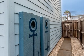 Una cerca de madera con una puerta que dice 'BEACH' y un sendero que lleva a la playa.