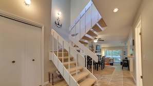 A spacious interior with a staircase leading to an upper level, a dining area, and a view of the outdoors. - Harbor Cove Condo | Ski • Beach • Explore (Harbor Springs)