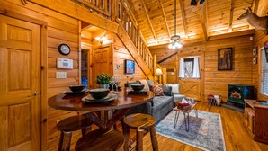 A wooden cabin interior with a dining area, staircase, and a fireplace. - *Starlink Wifi* Peaceful Log Cabin Near National Park & Dollywood (Sevierville)
