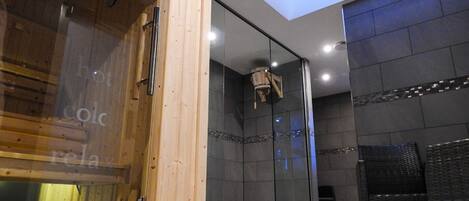 A modern spa room with a wooden door, a glass partition, and a ceiling light fixture.