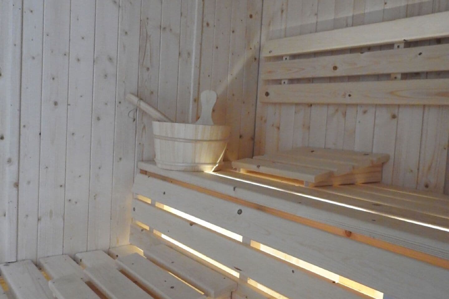 Una sauna con bancos de madera y un balde de madera.