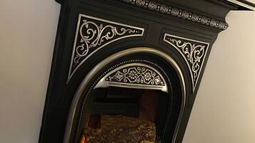 Une cheminée ornée de motifs complexes en noir et blanc, dotée d’un manteau en pierre et où l’on peut voir les flammes.