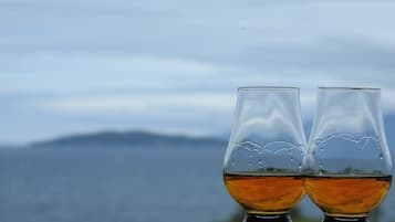 Två glas med en bärnstensfärgad vätska står på ett bord, och i bakgrunden syns ett vackert berglandskap.