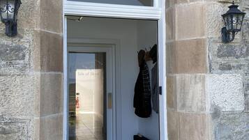 A stone archway leading to a door with a sign reading "House of Juniper."