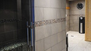 A modern bathroom with a glass shower enclosure, tiled walls, and a clock on the wall. - House Of Juniper - The Manse (Strath)
