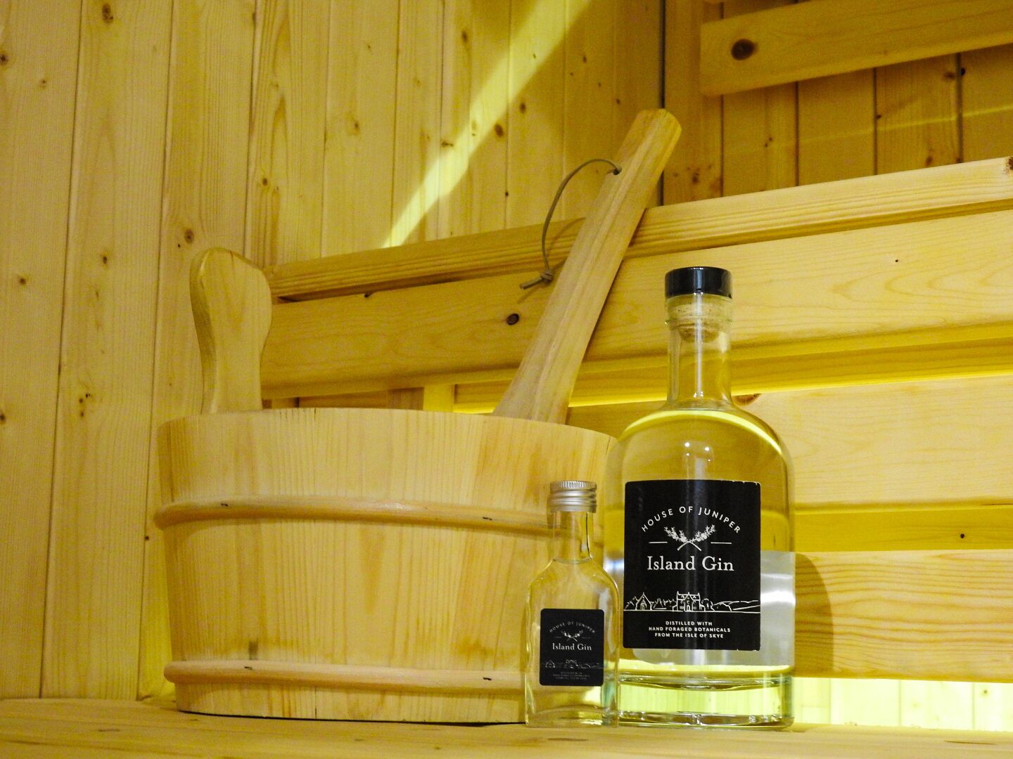 A wooden cabinet with a bottle of Island Gin and a smaller bottle of gin, both labeled with the same brand.