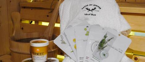 A wooden bath chair, a white towel, and three jars of body scrubs.