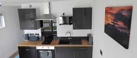 A modern kitchen with a dishwasher, oven, microwave, and a large window.