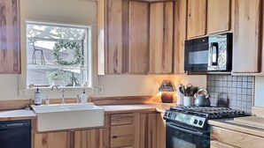 Una cocina moderna con gabinetes de madera, microondas integrado, estufa y un amplio ventanal con vistas al exterior.