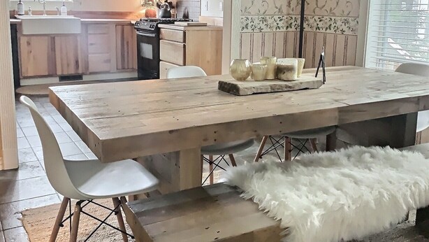 Una cocina moderna con armarios de madera, un comedor con una mesa y bancos de madera, y un papel tapiz estampado.