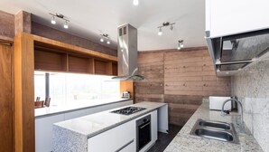 Een moderne keuken met een centraal eiland, roestvrijstalen apparatuur en een groot raam voor natuurlijk licht.