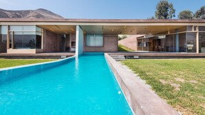 Een modern huis met een zwembad, grote glasramen en een plat dak.