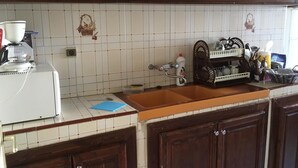 A kitchen with wooden cabinets, a white tiled backsplash, a coffee maker, and various kitchen utensils.