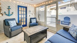 Una veranda illuminata dal sole con mobili in vimini, una porta blu e decorazioni a tema nautico.