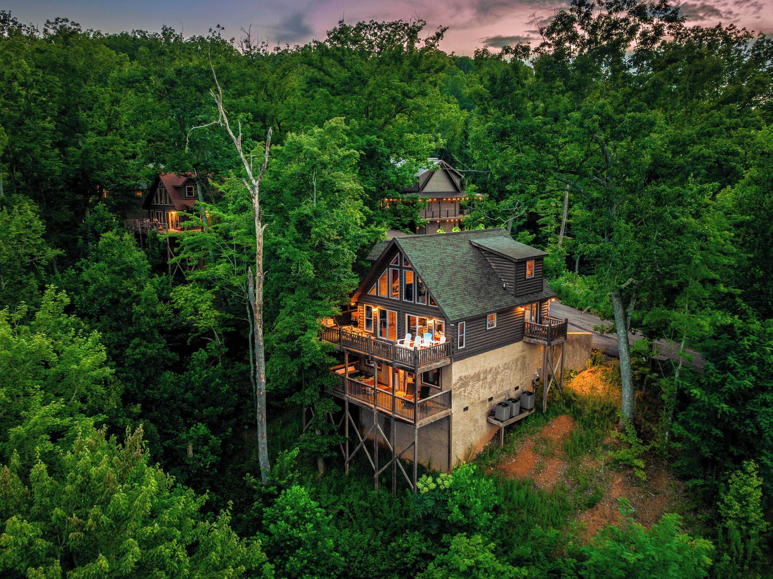 A cabin with a balcony, surrounded by dense forest.