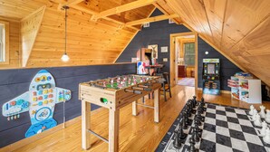 A cozy room with wooden beams, a foosball table, a foosball table, a foosball table, and a foosball table. - Smoky/ Mountain views/ King bed/ bunk bed/en suite bath/Hot tub/Sauna/Pet/value (Sevierville)