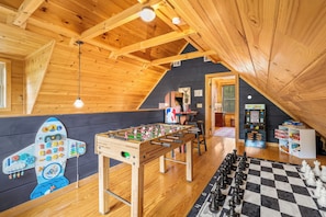 A cozy room with wooden beams, a foosball table, a foosball table, a foosball table, and a foosball table.