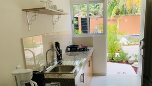 Una cocina con refrigerador, cafetera y ventana con vista a la vegetación.