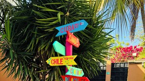 Un letrero colorido con flechas direccionales que indican varios destinos, incluyendo Cuba, Chile, Canadá, Cancún y París.