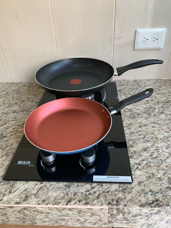 Deux poêles sur une cuisinière à gaz, le plan de travail étant en granit.