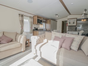 A compact living space with a sofa set, a small table, and a kitchenette area.