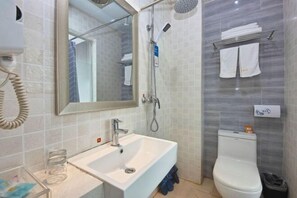A bathroom with a white sink, a mirror, a shower, and a toilet.