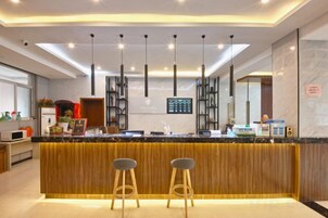 Una cocina moderna con una isla central, taburetes de bar, iluminación colgante y una pantalla digital con el menú.