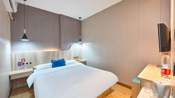 Una habitación de hotel moderna con una cama grande, mesitas de noche, una máquina de café y un televisor de pantalla plana montado en la pared.