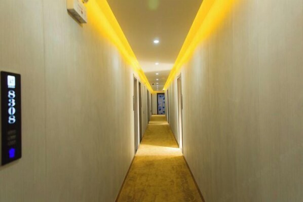 A hotel hallway with a carpeted floor and a number sign on the wall.