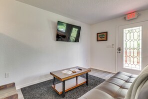 A room with a sofa, a table with papers, a painting, and a door with a stained glass window.