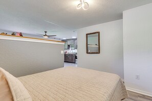 A bedroom with a bed, a ceiling fan, and a mirror on the wall.
