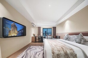 Una habitación de hotel moderna con una cama grande, un escritorio, un televisor de pantalla plana en la pared y vistas a la ciudad por la ventana.