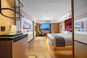 A hotel room with a bed, a desk, a chair, a small table, and a window with a city view. - Hongfangzi Hotel (Phoenix Lake Park) (Yuanmou)