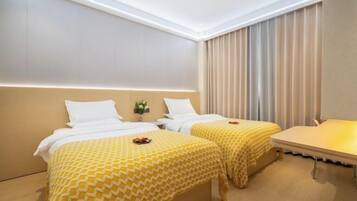 Ett hotellrum med två sängar, ett litet bord och utsikt över staden.