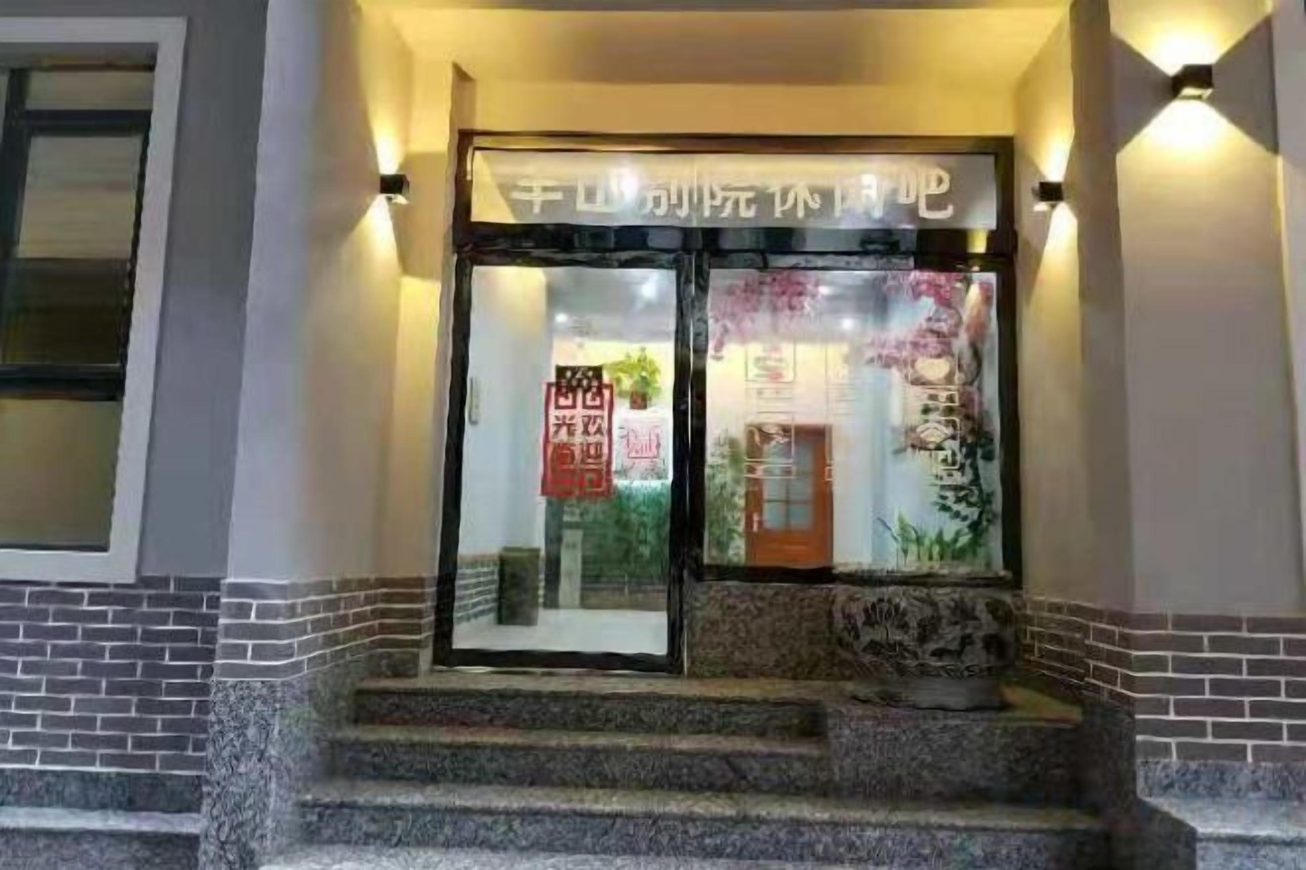 A hotel entrance with a glass door, steps leading up to it, and a sign above the door.