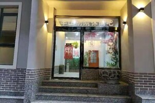 Entrada de hotel con puerta de vidrio, escalones que llevan a ella y un letrero sobre la puerta.