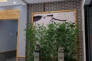 A room with a brick wall, a large painting, and a bamboo plant.