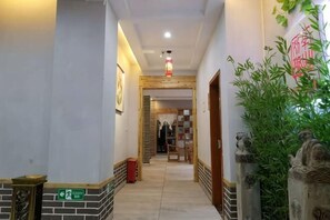 Un couloir d’hôtel avec une porte en bois, une poubelle et un panneau vert sur le mur.