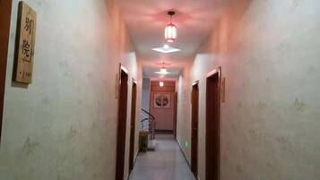 A hallway with a ceiling light fixture, a staircase, and a door on the right.