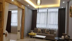A modern living room with a sofa, a coffee table, and a dining table. - Banshan Bieyuan Inn (Yanjin)