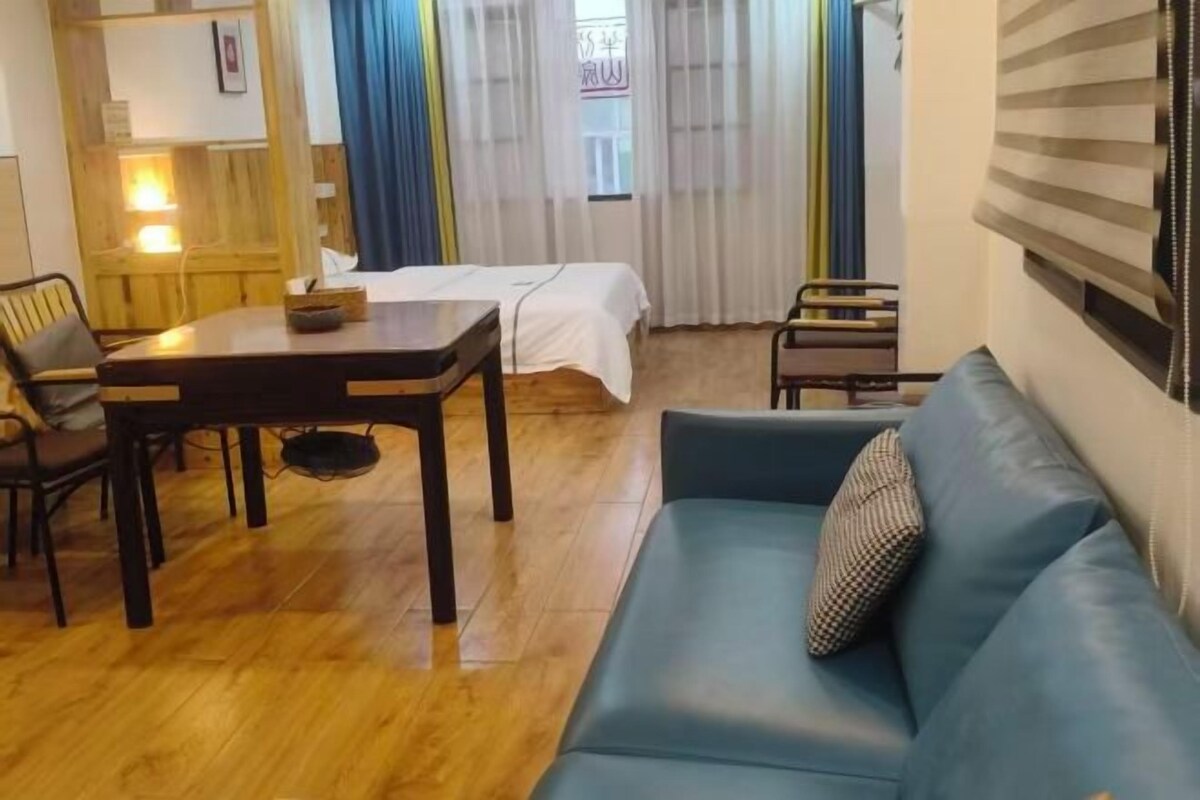A room with a bed, a blue sofa, a wooden table, and a chair.