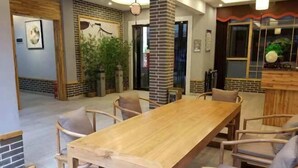 A dining area with a wooden table and chairs, brick walls, and a large potted plant. - Banshan Bieyuan Inn (Yanjin)