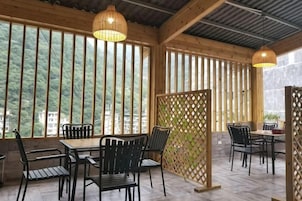 Un comedor interior con paredes de madera, ventanas amplias y mobiliario de metal negro.