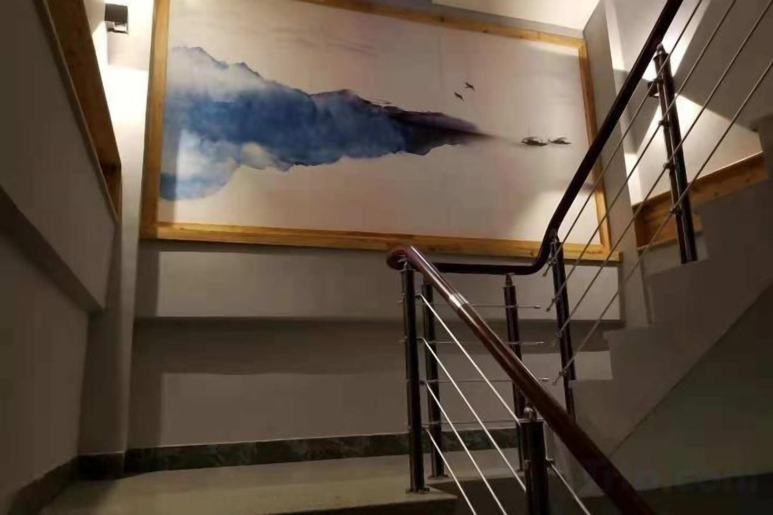 A staircase with a handrail and a wall-mounted artwork depicting a blue abstract scene.