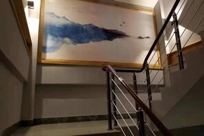A staircase with a handrail and a wall-mounted artwork depicting a blue abstract scene. - Banshan Bieyuan Inn (Yanjin)