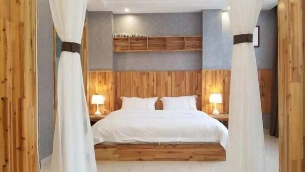 A bedroom with a wooden headboard, two bedside tables with lamps, and a bed with white bedding. - Banshan Bieyuan Inn (Yanjin)